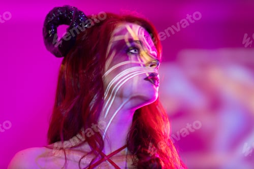Preview: woman with makeup zodiac signs of Aries sign horoscope. Girl with horns on head in neon light.