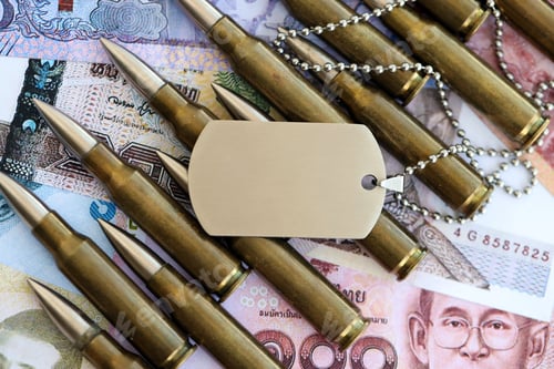 Preview: Thai baht currency money bills and rifle bullets with dogtag. The concept of warfare and army