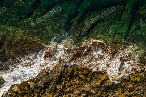 Preview: Ocean waves crashing on rocks on the beach, aerial drone view