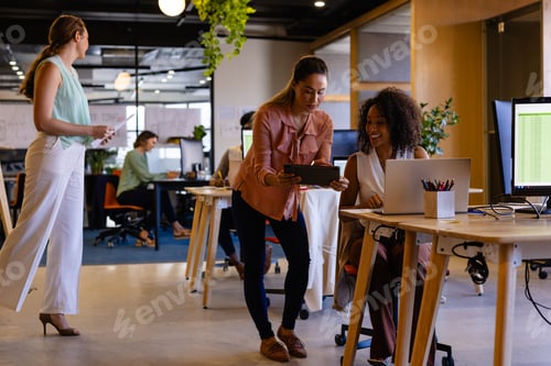 Preview: Diverse female colleagues in discussion using tablet in casual office meeting