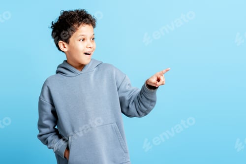 Preview: Handsome little boy pointing finger on copy space isolated on blue background. Advertisement concept