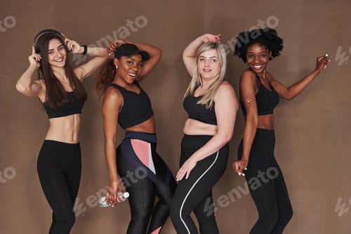 Preview: Group of multi ethnic women standing in the studio against brown background