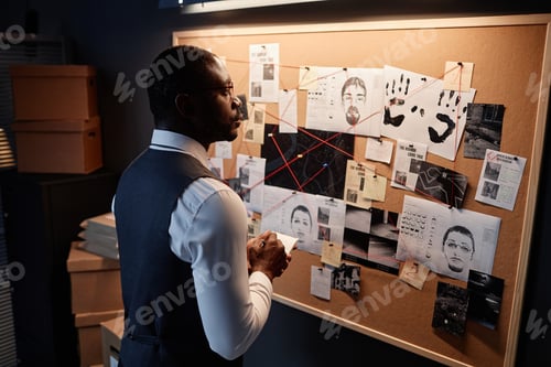 Preview: African American detective looking at evidence board in office