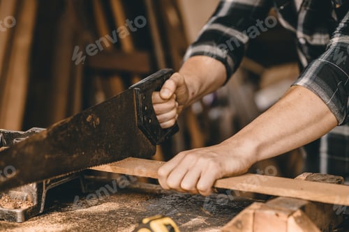 Preview: Closeup male builder worker hand using wood saw to sawing wood in furniture workshop.