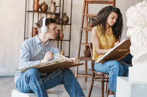 Preview: Young two student in headphones drawing plaster bust at art school