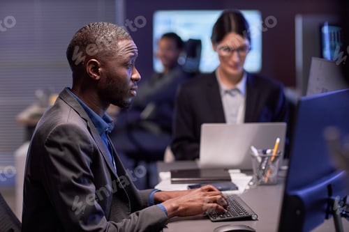 Preview: Serious black businessman using laptop at workplace in IT office