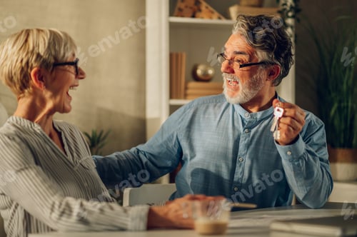 Preview: Senior couple sitting at table and looking into blueprints of their new home