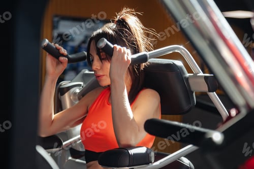 Preview: Woman does sports in gym of fitness center, performing exercises on simulators. Sports activities