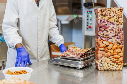 Preview: Close up of a scale weighing almonds with worker in the background at a food packaging facility