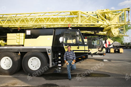 Preview: Man smiling in front of a large yellow mobile crane
