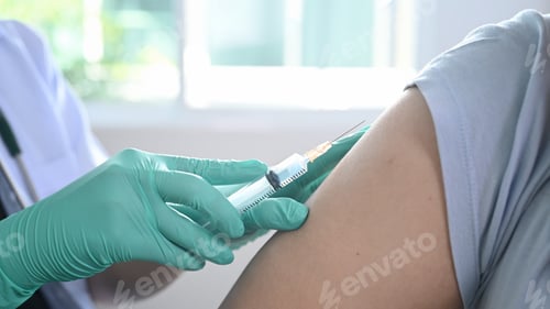 Preview: Close up view of doctor holding syringe and giving injection to patient at hospital.