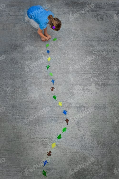 Preview: View from overhead of a child creating and walking along a line of coloured leaf shapes.