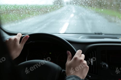 Preview: Woman driving car on rainy day, closeup of hands