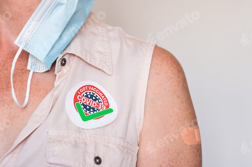 Preview: Sticker I Got Vaccinated COVID-19 on woman’s chest with face mask off and bandage on vaccine site