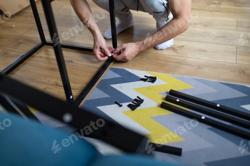 Preview: Man assembling furniture at home in the living room. Young man sitting on the floor and reading inst