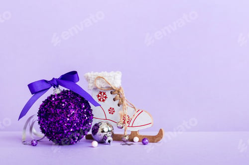 Preview: Christmas ball with skates on colored background. decoration bauble with ribbon bow with copy space