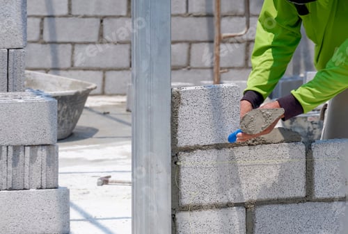 Preview: Bricklayer hand using trowel to making brick wall inside of house construction site