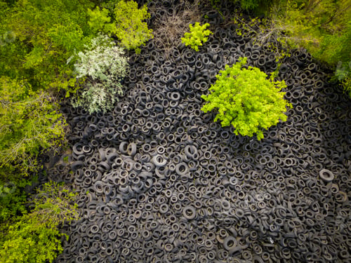 Preview: Aerial view of the stark contrast between a massive landfill of used car tires and the surrounding