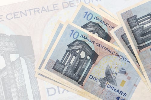 Preview: 10 Tunisian dinars bills lies in stack on background of big semi-transparent banknote. Abstract pre