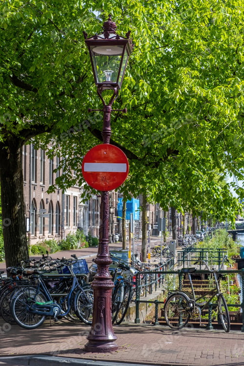 Preview: Stop sign in Amsterdam Netherlands Holland. Bike parked on a canal bridge, traditional houses