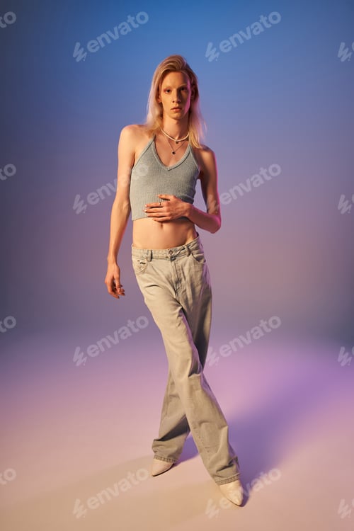Preview: vertical shot of attractive sexy androgynous person in stylish attire looking at camera in lights