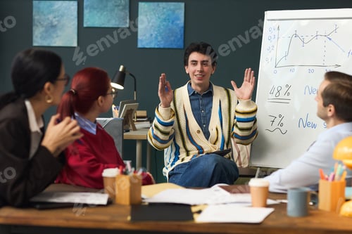 Preview: Young Man Gesturing While Leading Business Presentation for Team
