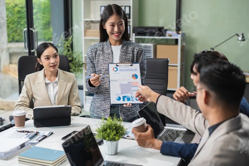 Preview: Asian businessman showing hand and smiling young team of colleagues making good business discussion