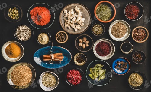 Preview: Flat-lay of different spices in bowls over dark background