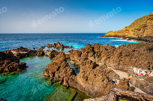 Preview: Expansive body of water situated near a large rock formation, with jutting cliffs and rugged terrain