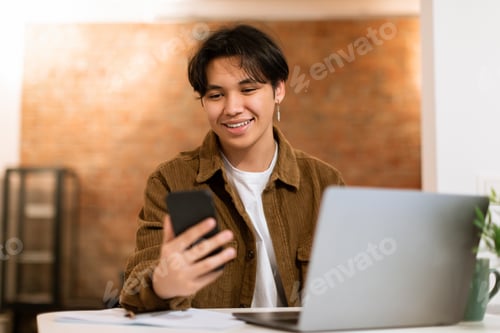 Preview: Korean Teen Boy Using Phone Learning Sitting At Laptop Indoors