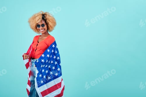 Preview: Smiling afro woman holding an USA flag while standing on an isolated background.