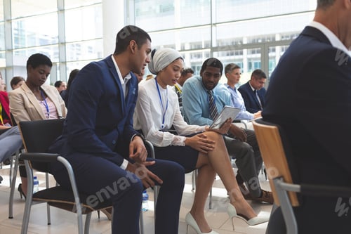 Preview: Diverse business people discussing over digital tablet during seminar in office building