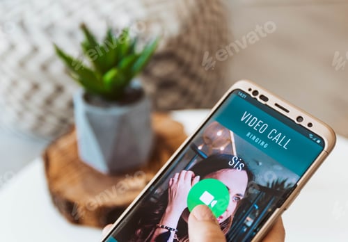 Preview: Close-up of hand holding mobile phone with incoming video call ringing.