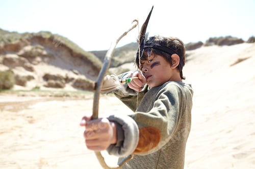 Preview: Young boy wearing fancy dress, holding home-made bow and arrow