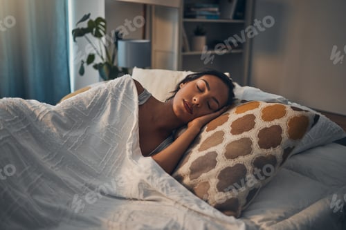 Preview: A beautiful young mixed race woman sleeping in a soft comfortable bed at home. One hispanic female
