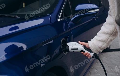 Preview: Human hand is holding Electric Car Charging connect to Electric car