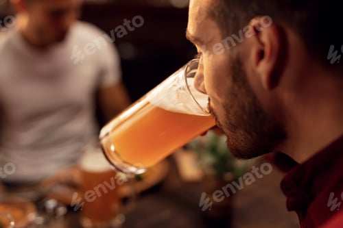 Preview: Close up of man drinking beer in a bar.