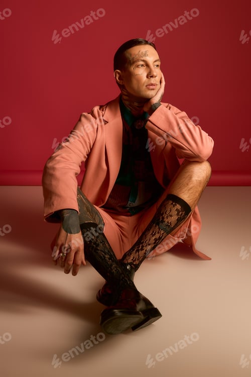 Preview: Stylish man in pink suit poses gracefully against a vibrant backdrop