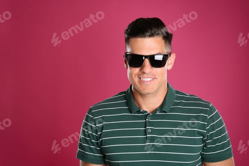 Preview: Handsome man wearing sunglasses on pink background