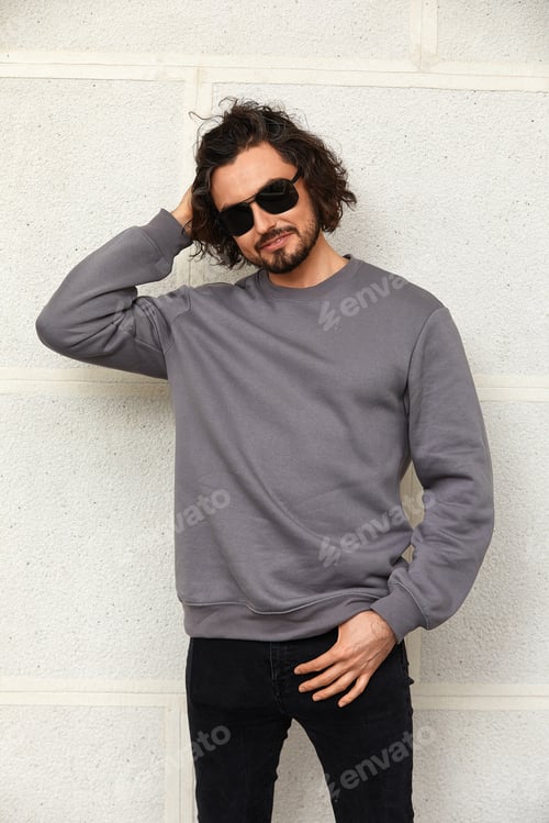 Preview: Modern young man in sunglasses with long hair, handsome man in glasses on the background of the wall