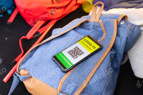 Preview: Close-up of covid-19 vaccination certificate on the smartphone on a backpack