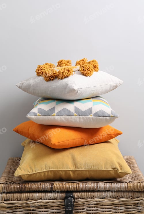 Preview: Soft pillows on wooden trunk near light grey wall