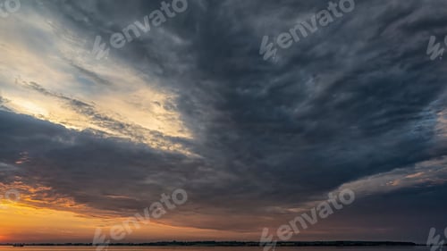 Preview: Faro island with dramatic sunset sky with gloomy clouds visible from Stubbekobing in Denmark.