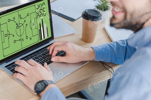 Preview: cropped shot of smiling businessman in headset using laptop with soccer strategy on screen