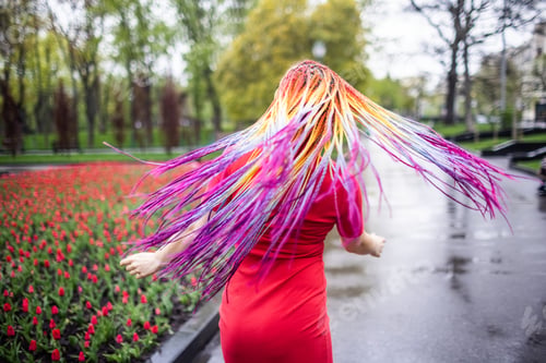 Preview: Cute girl with multi-colored African braids and bright expressive makeup in a tight red dress is