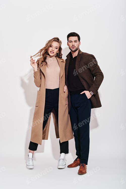 Preview: Looking perfect together. Attractive and well-dressed couple posing in studio. Isolated over grey