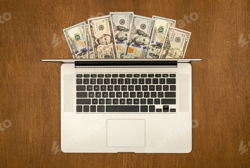 Preview: Laptop and dollar bills on wooden background, flat lay.