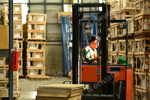 Preview: Warehouse worker in uniform loading cardboard boxes with forklift in warehouse.