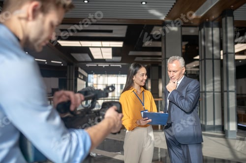 Preview: Asian female reporter in beige pants making motes