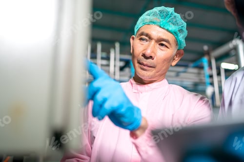 Preview: worker working in drink factory at conveyor belt with fruit juice glass bottled in production line